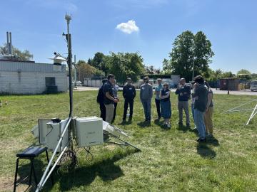 A group stands behind scientific monitoring equipment under a blue sky