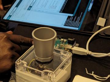 An open hardware sensor sits next to an open laptop