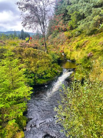 River running through green countryside, with people in high visibility jackets in background