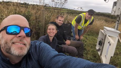 Four field technicians repairing a faulty rain gauge
