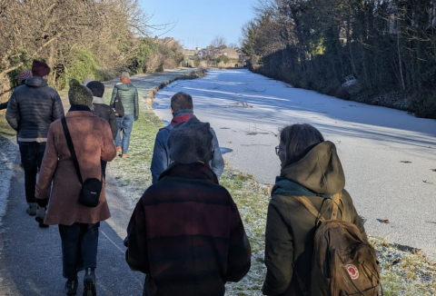 A group of people walk beside a frozen river