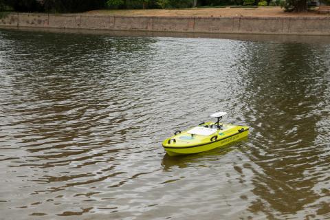 A yellow-green remote controlled boat on a stretch of river