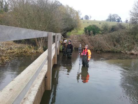 Jasmine Hughes stood in a river conducting her gauging work with two men from the River Chess Association
