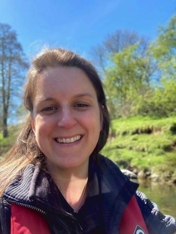 Portrait image of Verity Flett smiling with a river in the background