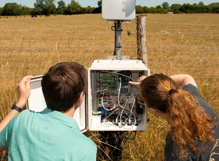 Colleagues in a field inspect the hardware in a COSMOS sensor