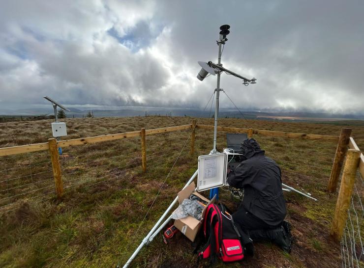 Person in raincoat getting measurements from a monitoring station