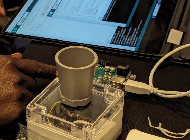 An open hardware sensor sits next to an open laptop